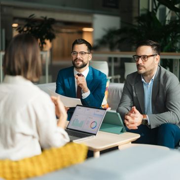 Two men interviewing a woman in a modern office setting.