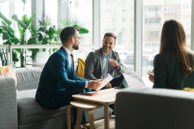 Three professionals in a business meeting, discussing with a laptop and documents.