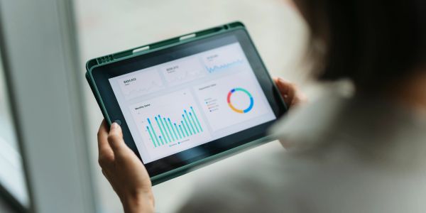 Person analyzing data charts on a tablet device.