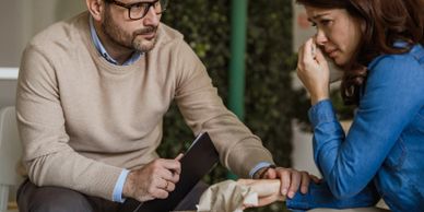 A man comforts a distressed woman during a conversation.