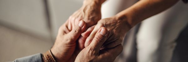 Two people holding hands in comfort.
