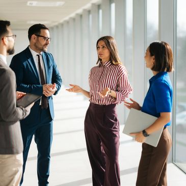 Four professionals having a discussion in an office corridor.