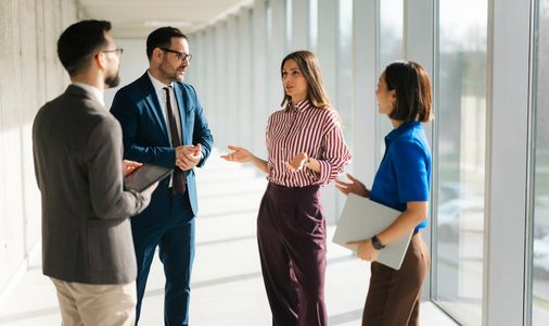 Four professionals engaged in a discussion in a bright office.