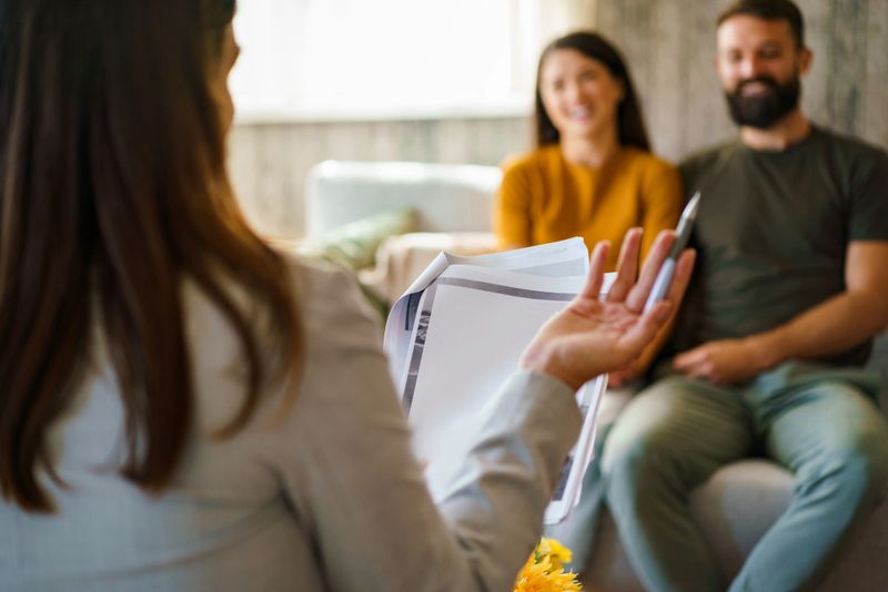 Counselor discussing document with a smiling couple during a therapy session.