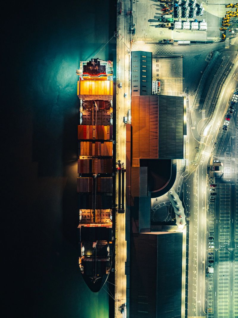 Cargo ship docked at a brightly lit container terminal, representing global logistics and shipping