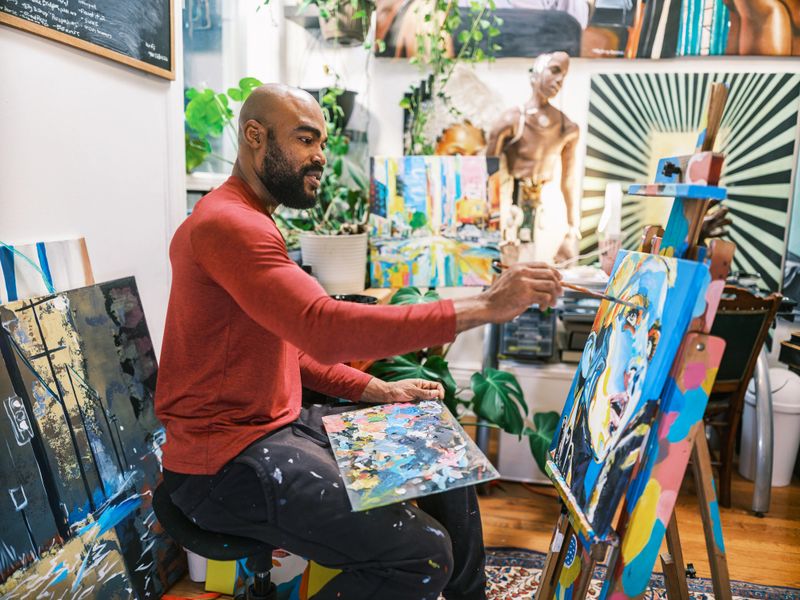Young black artist painting a portrait of his Caucasian girlfriend. He is  dressed in casual clothing. Interior of artist studio in Toronto, Canada.