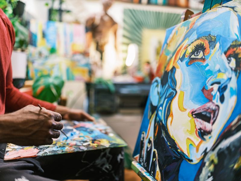Young black artist painting a portrait of his Caucasian girlfriend. He is  dressed in casual clothing. Interior of artist studio in Toronto, Canada.