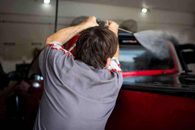 Mature man cleaning different parts of a van with a pressure washer at a professional car wash - Buenos Aires - Argentina