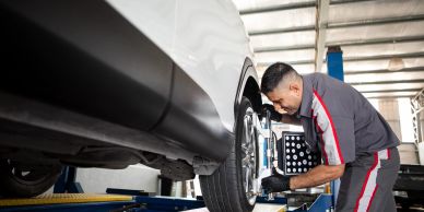 Technician inspecting a car tire in a garage.