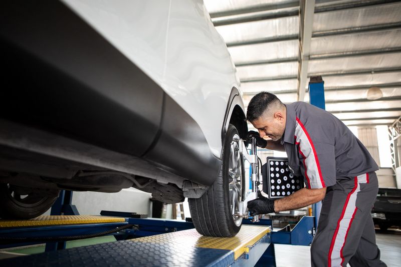 Male mechanic working on a computer setting the alignment and balancing of car tires in a mechanic's workshop -  Alignment and balancing car tires using professional technological tools on a computer - Buenos Aires - Argentina