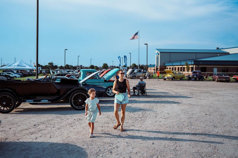 A mother and her young daughter walk past vintage cars during the Show and Shine event at Cruise Nite in Kearney, Nebraska.