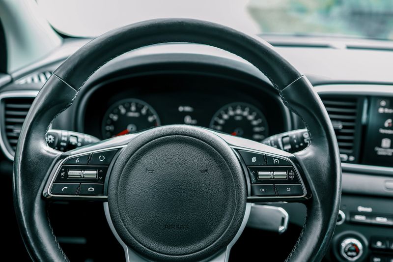 Close-up view of a car's steering wheel, dashboard, and infotainment system, showcasing contemporary automotive design and technology
