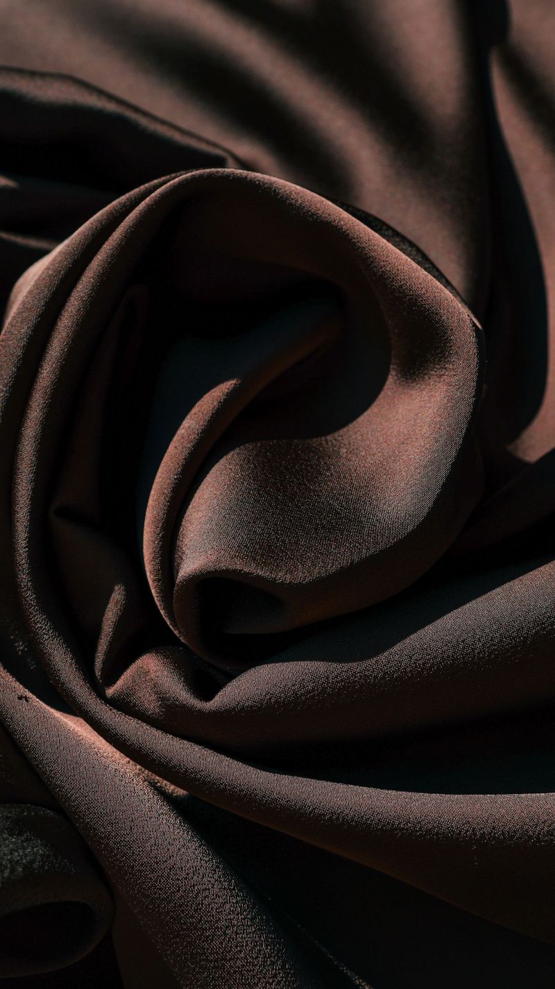 The rich texture of draped fabric is highlighted by strong contrasts of light and shadow, creating a sense of depth and luxury
