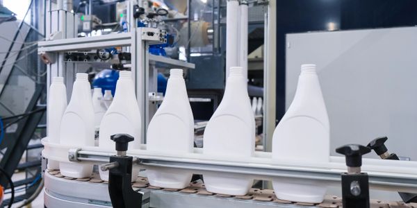 White plastic bottles moving on a conveyor belt in a factory.