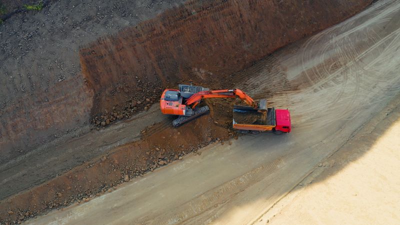 Excavator loading dirt into a large dump truck on an open-pit construction site