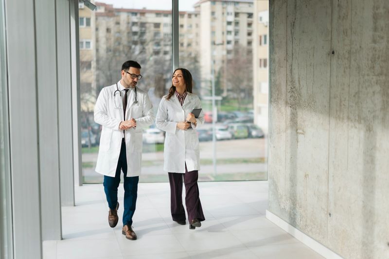 Medical professionals walking through hospital hallway discussing patient care