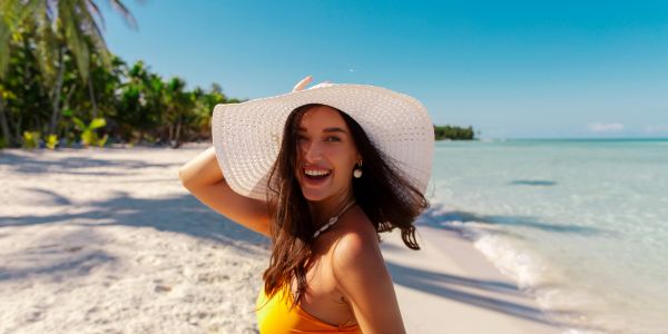 Smiling woman in a sunhat on a beach.