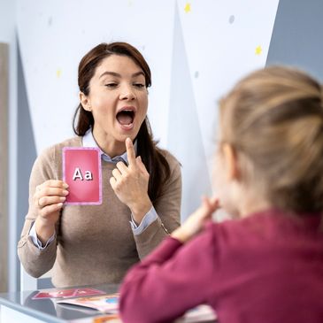 Teacher showing a flashcard to a child for learning.