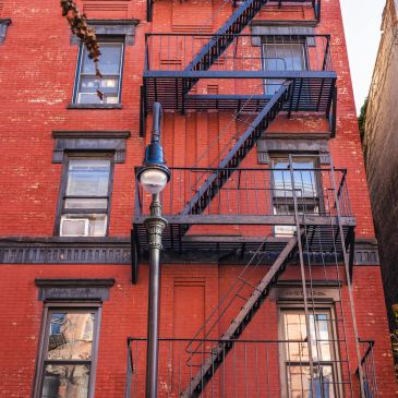 Red brick building with black fire escape and street lamp.