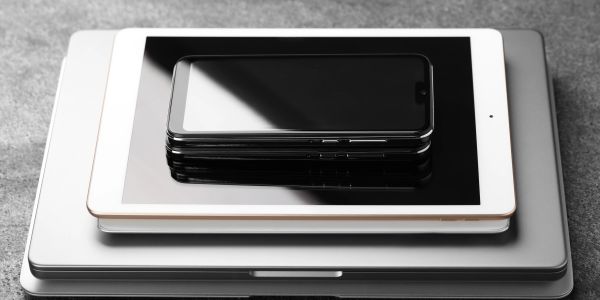 Stack of electronic devices including phones, tablet, and laptops.