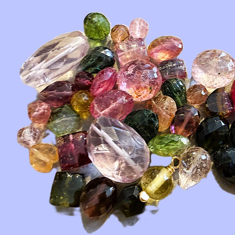 Close-up composition of vibrant gemstones featuring deep purple amethyst, clear blue aquamarine and multicolored tourmaline stacked together on a clean neutral background. Brilliant sparkle, crisp detail and natural reflections highlight the raw beauty of precious stones—ideal for themes of luxury, jewelry design, minerals, color variety and high-end fashion.
