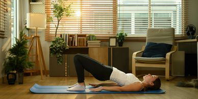 Woman doing bridge exercise on a yoga mat in a cozy room.