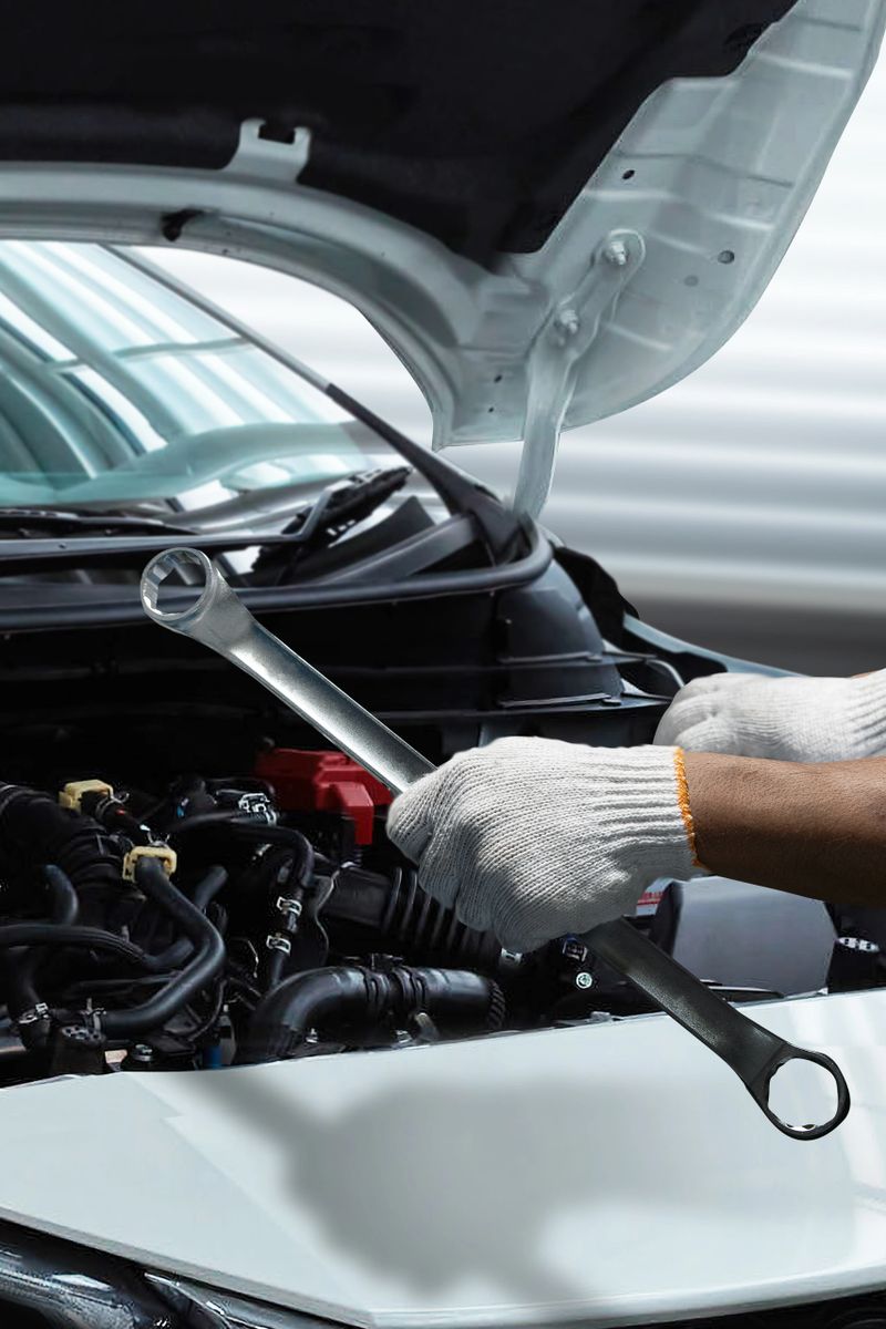 Vertical close-up image of a professional automotive mechanic holding a wrench while inspecting a car engine under the open hood. Ideal for mobile advertising, automotive service promotion, vehicle maintenance campaigns, and transportation industry concepts. Clean composition with space for text overlay.