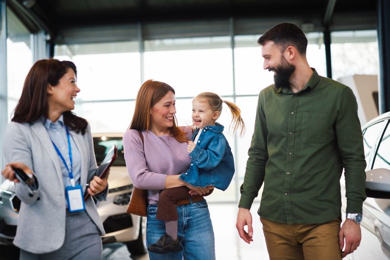 Happy family with car dealer after buying new vehicle