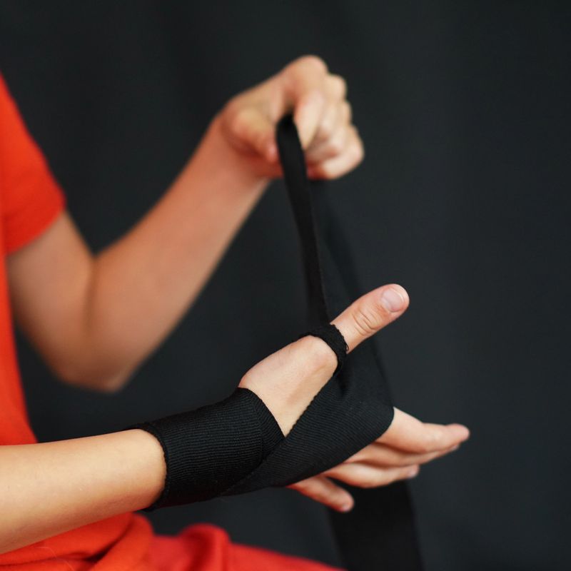 Teenage boxer's hands putting on black protective tape, concentrating before a boxing match