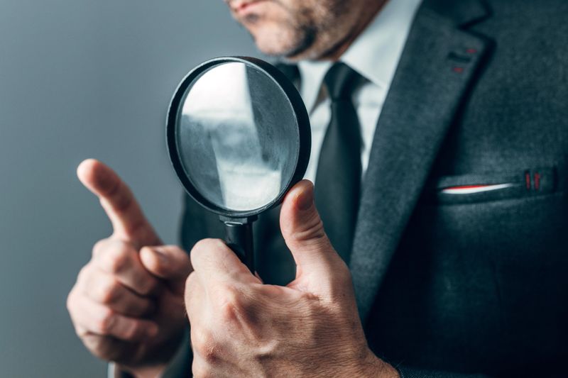 Businessman pointing magnifying glass forward, intense investigation portrait, selective focus