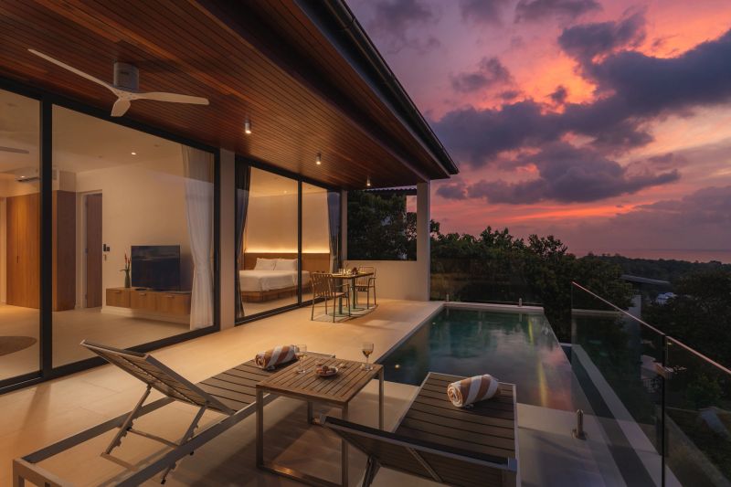 Private villa terrace with infinity pool overlooking the ocean and dramatic sunset sky.