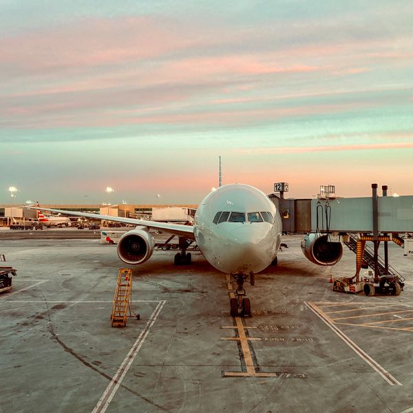 Airplane docked at airport gate during sunset, ready for boarding.