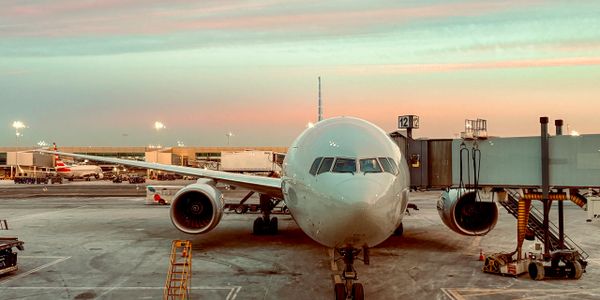 Airplane docked at airport gate during sunset, ready for boarding.