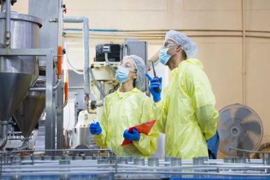 Two workers in protective gear inspecting machinery in a factory.