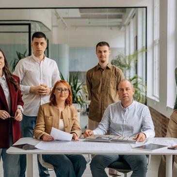 A group of professionals in a modern office setting gathered around a table with documents.