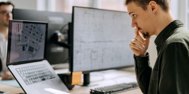 Man studying blueprints on paper and computer screens.