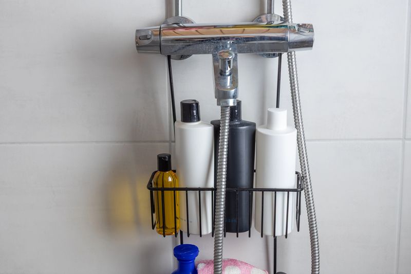 A shower caddy holds various personal care bottles, including shampoo and conditioner. The rack hangs from the showerhead, offering convenient storage for bathing essentials.