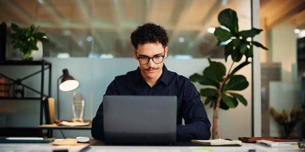 Young startup founder working on his laptop in a modern office.