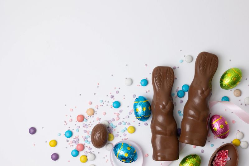 Chocolate Bunny And Eggs Scattered Across Pastel Table Creating Festive Easter Sweets Spread With Colorful