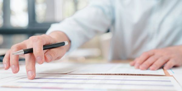 Person working with documents and pen on a table.