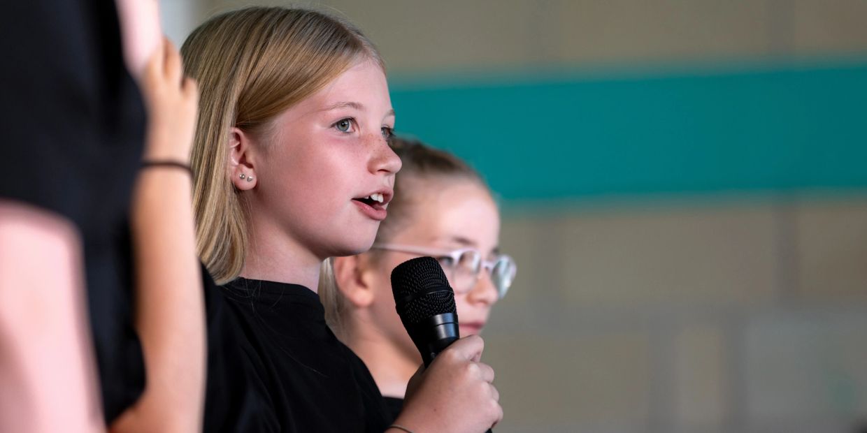 Young girl speaking into a microphone during an event.