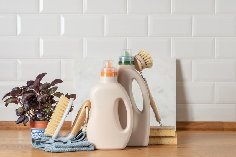 Eco friendly cleaning products in bottles with brushes and cloths on bright kitchen background