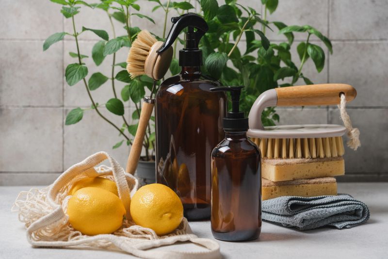 Eco friendly cleaning concept with glass bottle detergent, natural brushes and sponges on background of green plants, zero waste sustainable home cleaning idea