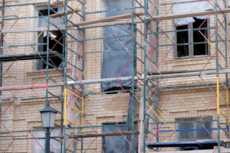 Workers are busy renovating a historic building covered in scaffolding.