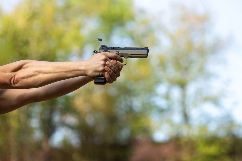Action shot of a pistol being fired with an empty shell casing flying in the air.