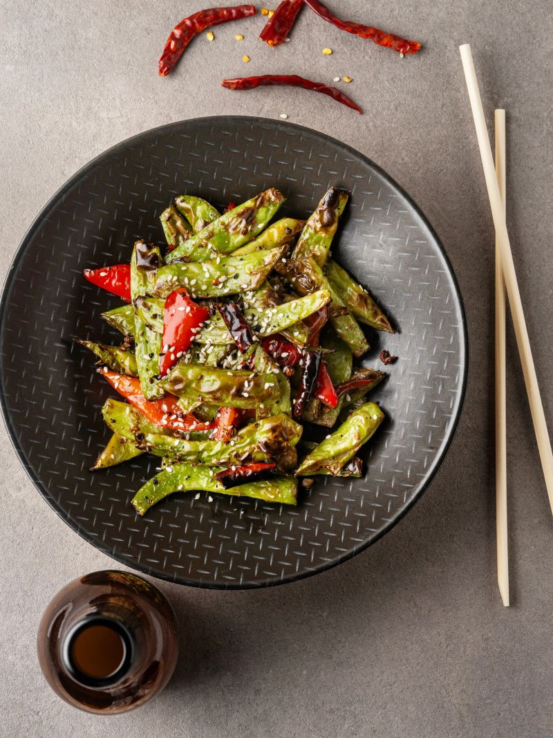 Spicy wok-fried green beans with red chili and sesame seeds, served with a bottle of Kombucha.