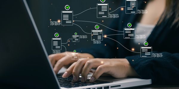 Person typing on laptop with digital document icons floating.