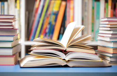 Open book with stacks of books on each side.