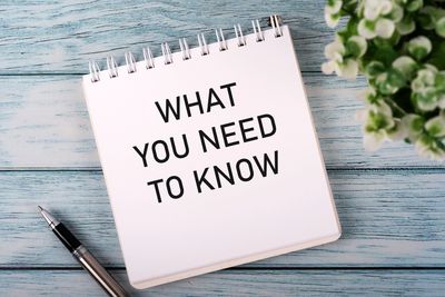 Notepad with 'What You Need to Know' text and a pen.