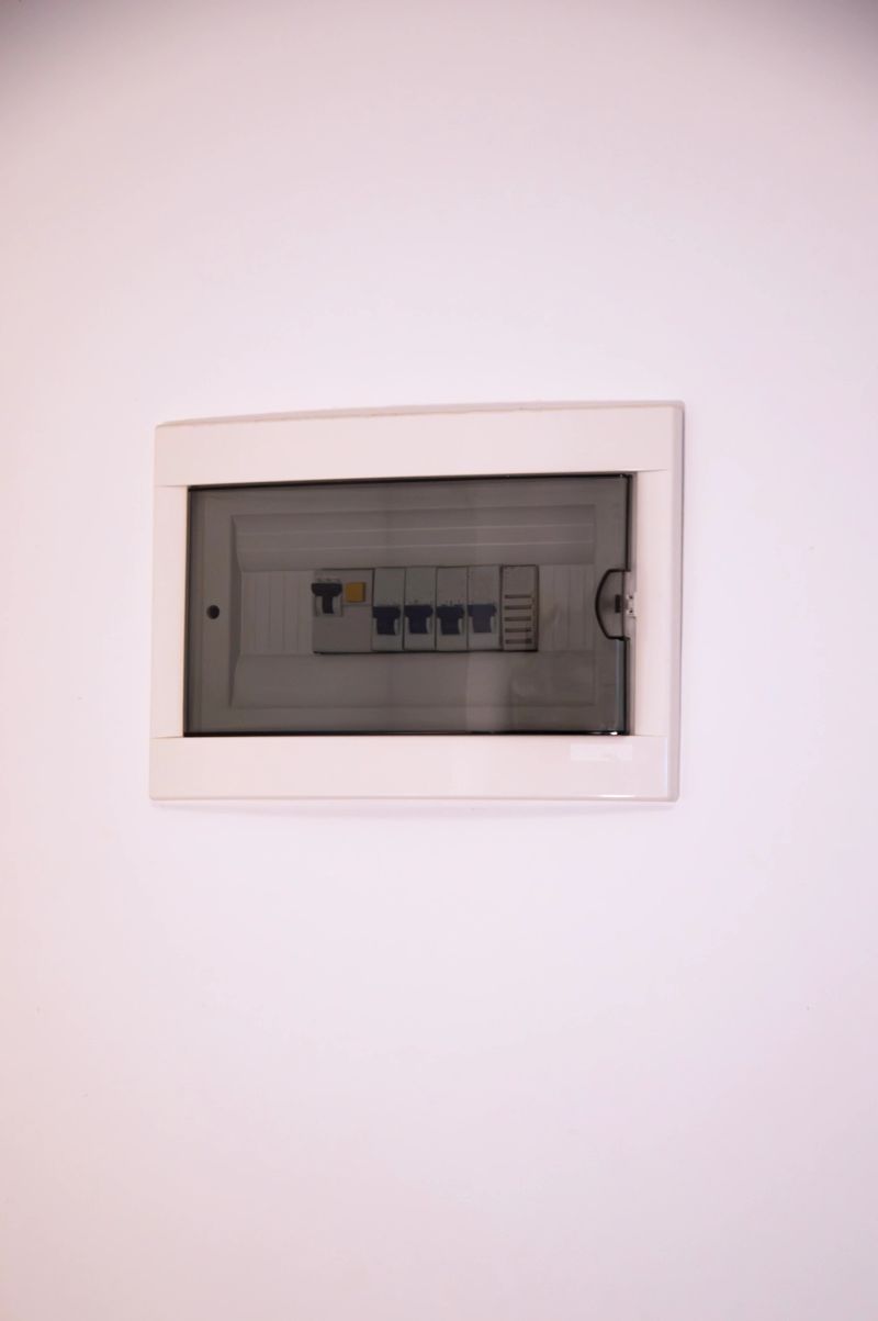 Front view of a modern electrical circuit breaker panel with protective cover on a white wall, symbolizing home electricity, power distribution, safety systems, and residential infrastructure